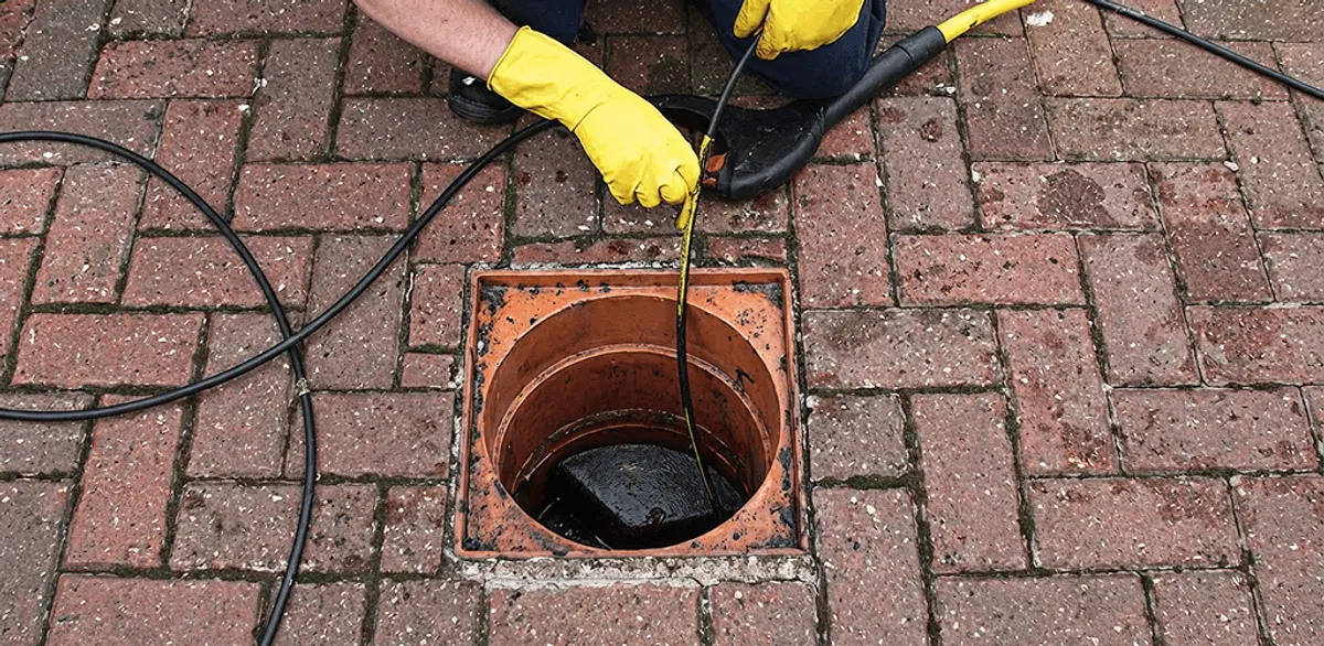Drain cleaning technician using a drain snake to clear a clogged drain in Omaha, NE