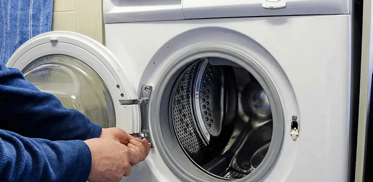 Washing machine repair handyman checking a front-load washer door and latch in Omaha, NE