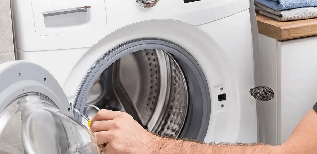 Handyman repairing a front-load washing machine and inspecting the drum in Omaha, NE
