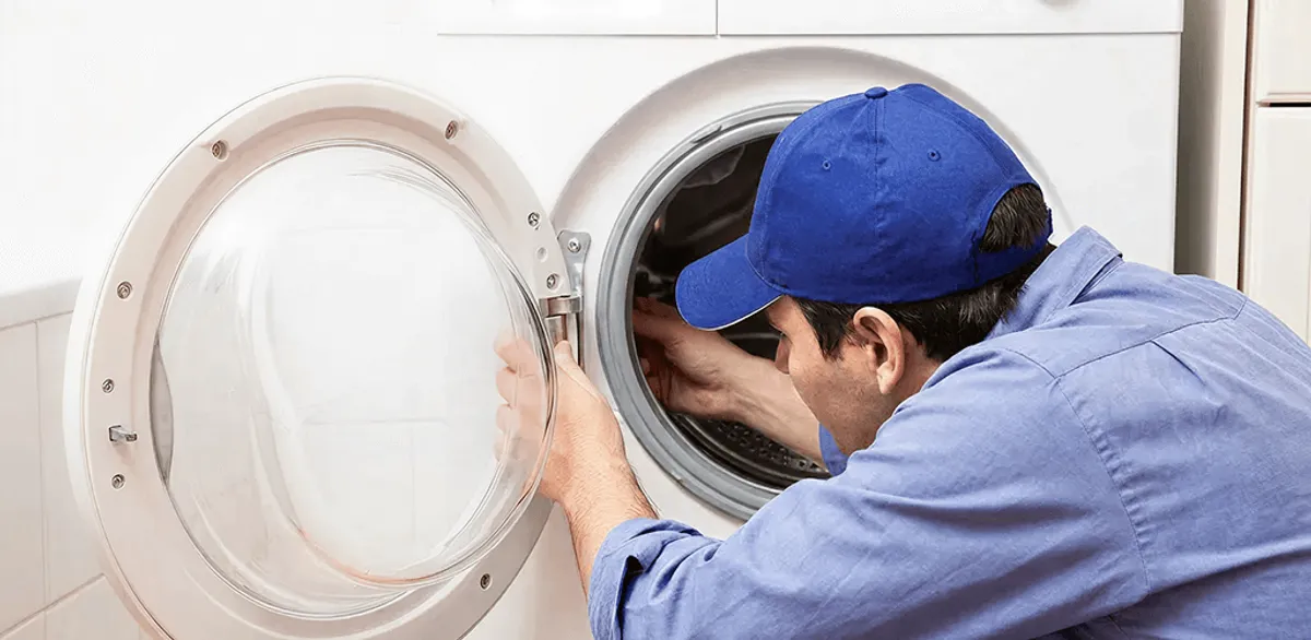 Washing machine repair handyman inspecting a front-load washer drum in Omaha, NE